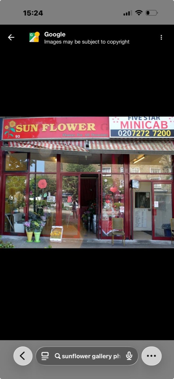 The original Sunflower shopfront, with its red and gold sign, striped awning and flowers by the entrance.
